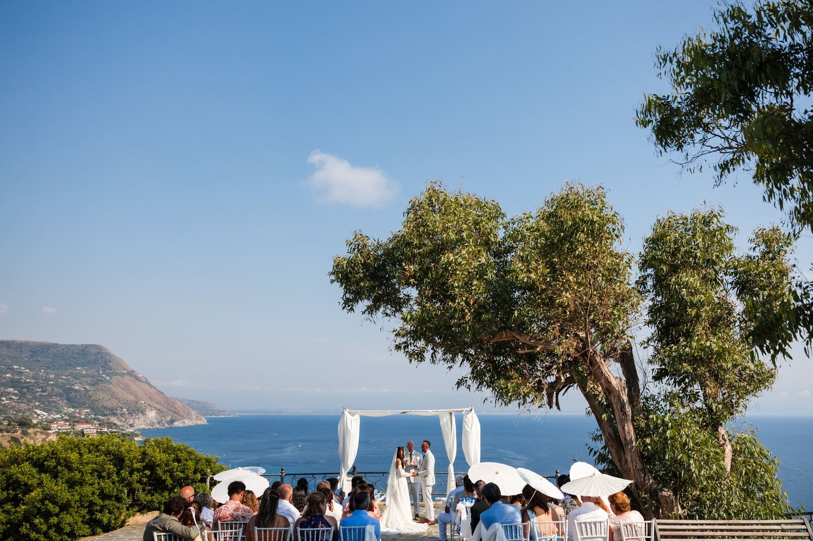 A ceremony under the trees with the coast behind