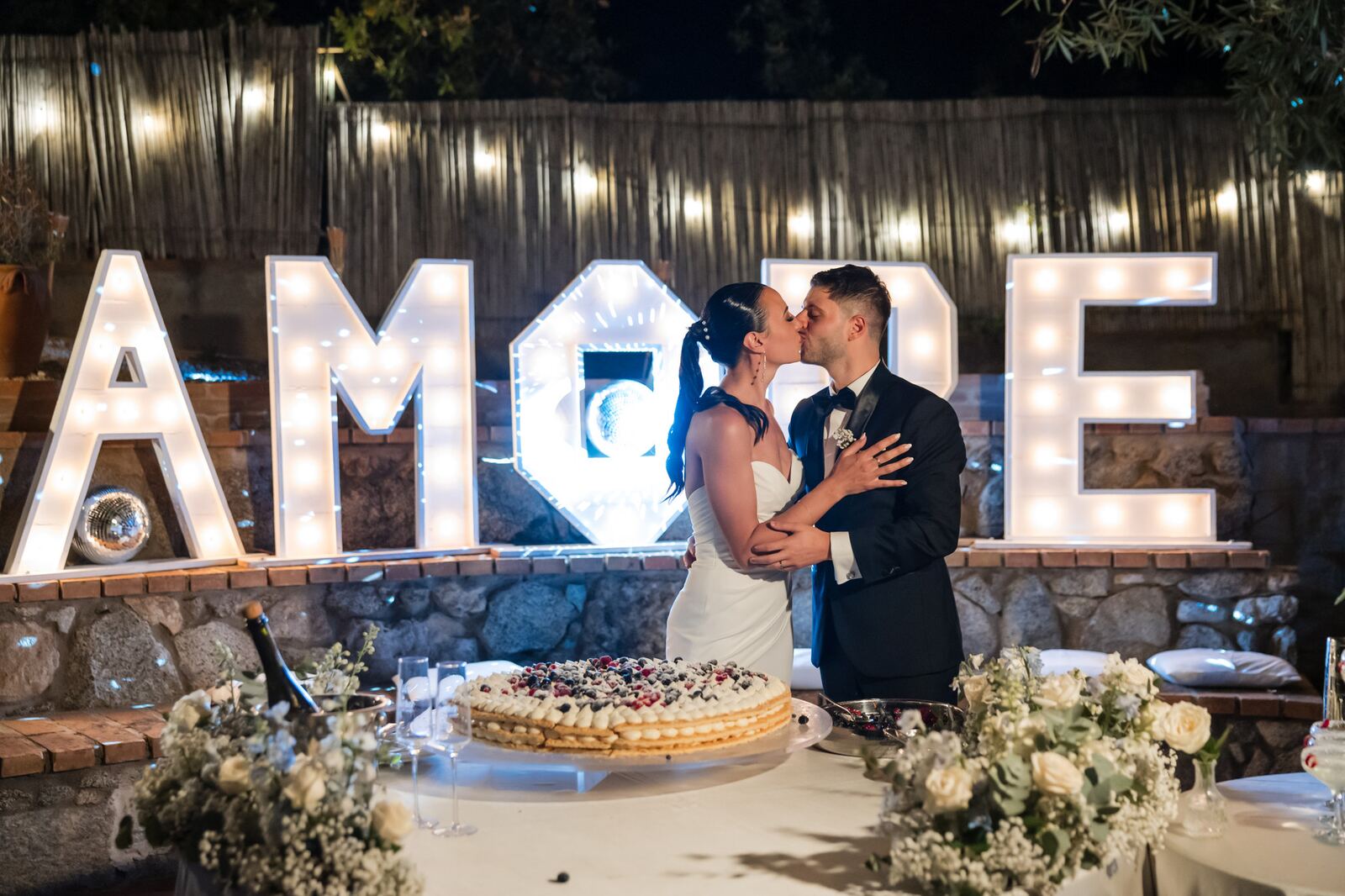 Cutting the cake in front of the AMORE sign